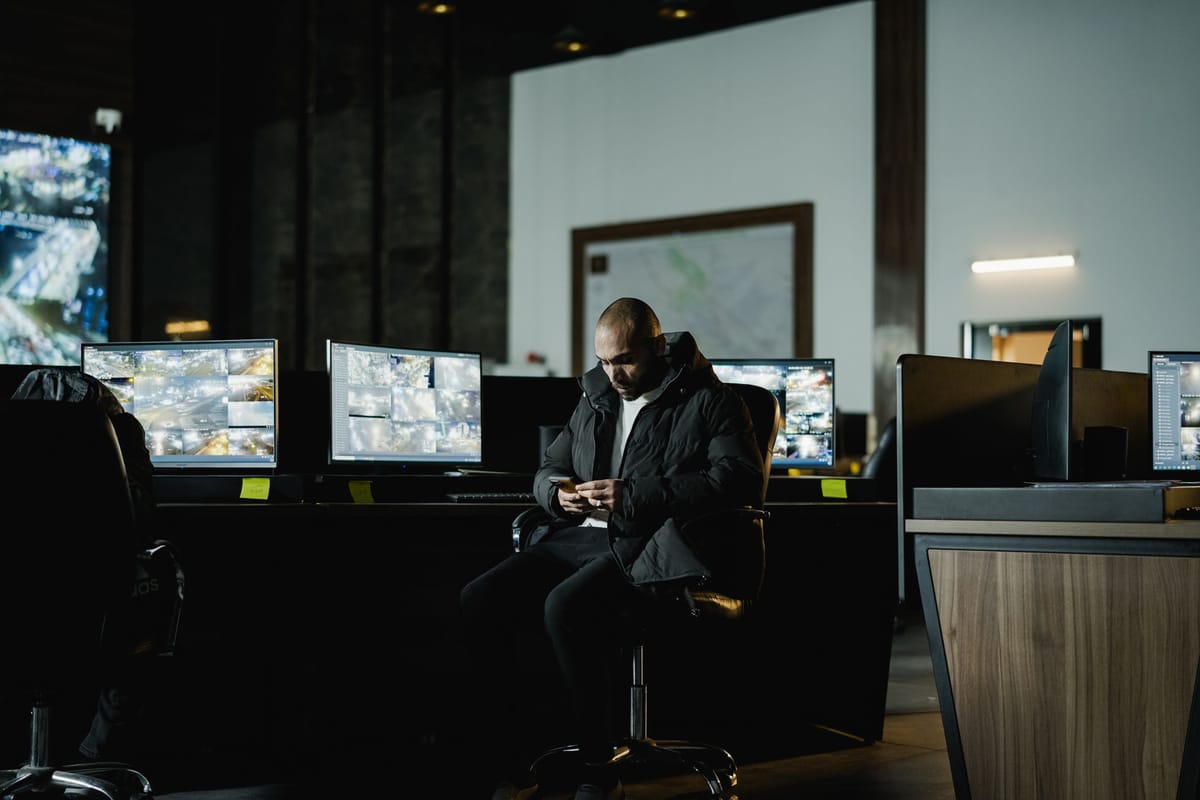 Security officer analyzing multiple surveillance screens in a control room, representing AI governance and audit monitoring